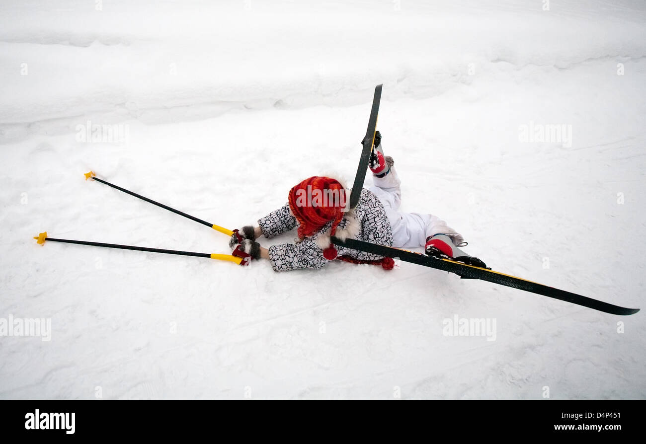 Niña en esquís y bastones de esquí tumbado en la nieve Fotografía de stock  - Alamy