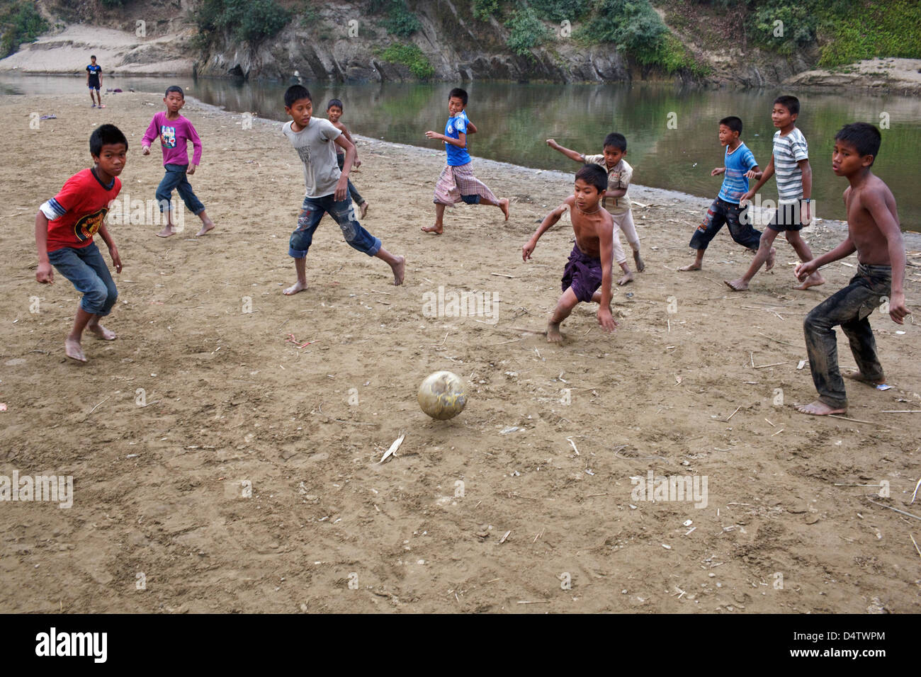 Niños jugando fútbol en la playa fluvial de Bandarban, Bangladesh Foto de stock