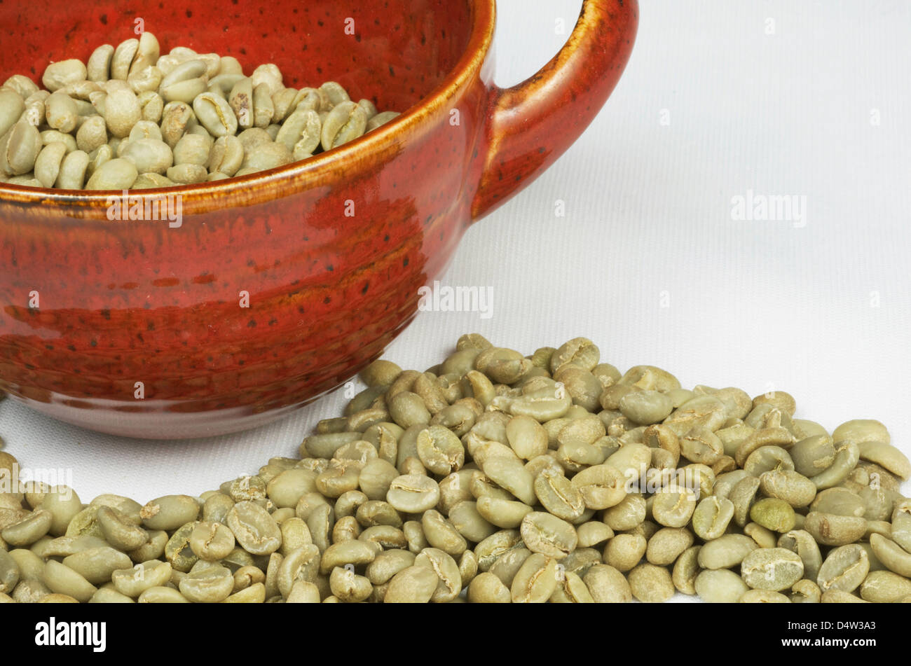 Los granos de café verde con taza roja Foto de stock