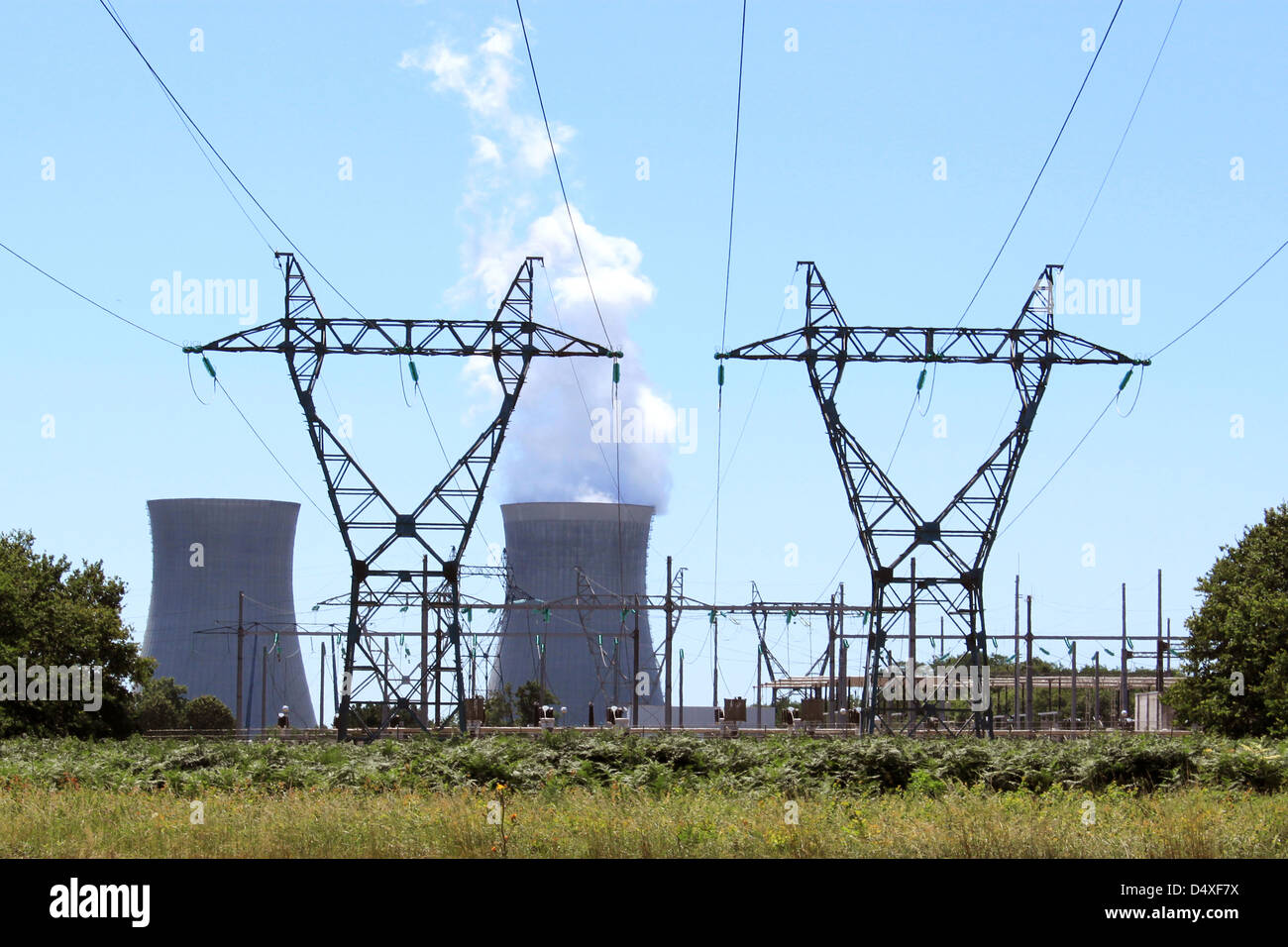 Torres eléctricas en frente de una planta de energía nuclear Foto de stock