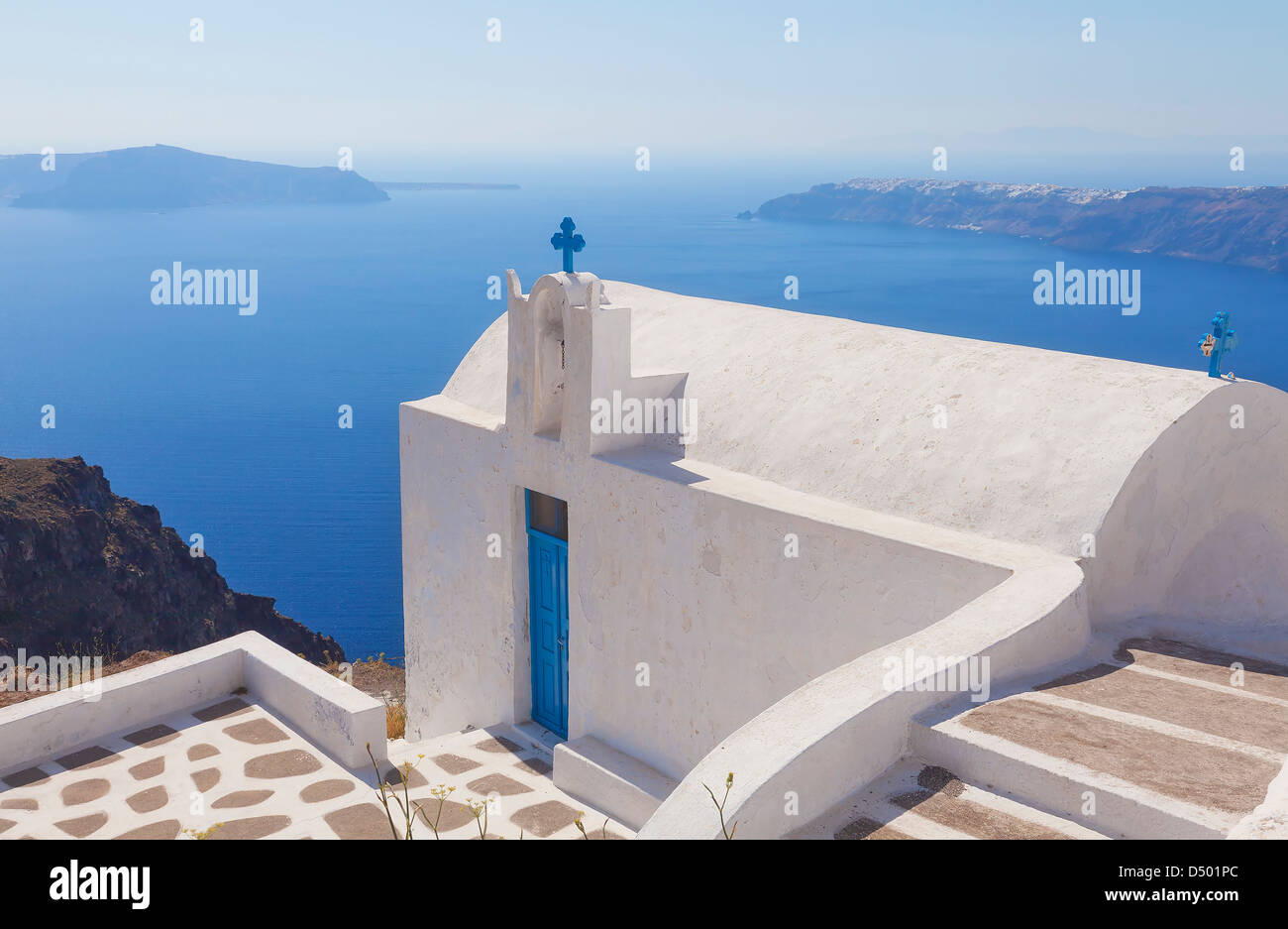 Pequeña iglesia desde lo alto del acantilado en Imerovigli en la isla griega de Santorini. Foto de stock