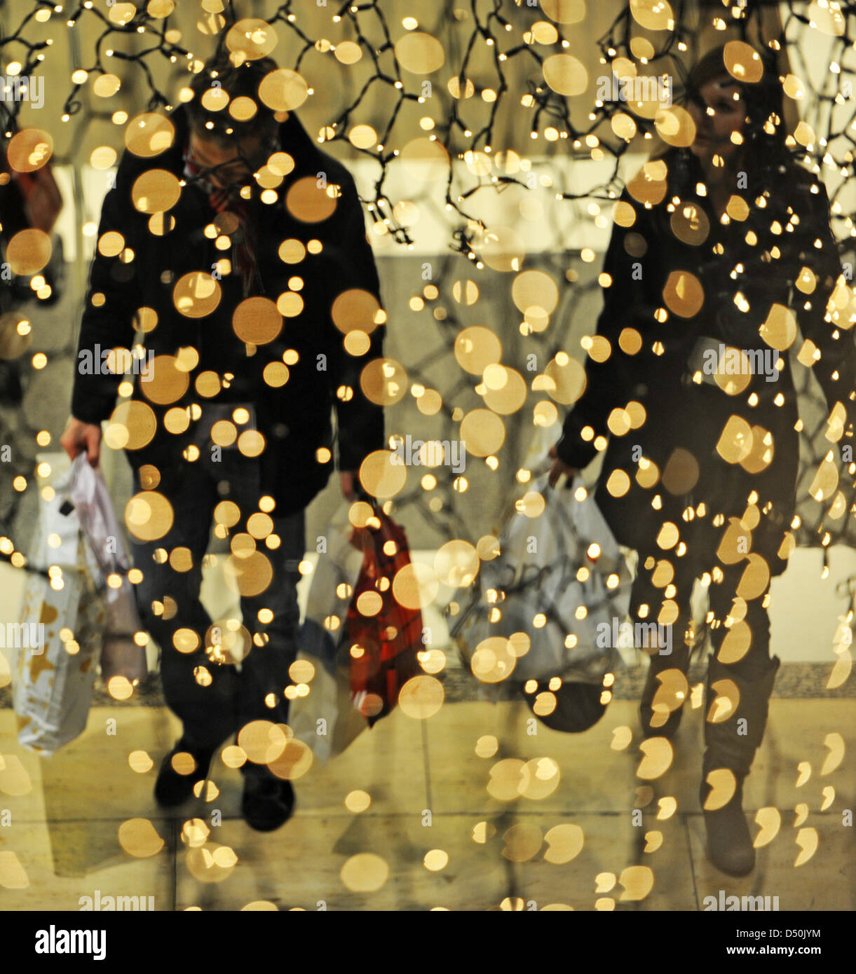 Las personas con bolsas de compras salir de una tienda de zapatos que está decorado con luces de Navidad en Munich, Alemania, el 25 de noviembre de 2010. Los vendedores minoristas de Baviera la esperanza de hacer un buen comercio navideño. Foto: Marc Mueller Foto de stock