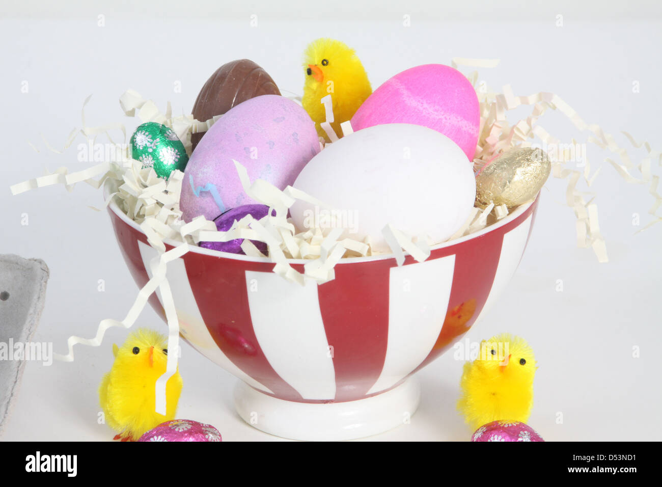 Tinte huevos pintados de blanco y un huevo en un cuenco lleno de paja, papel decorado para la Pascua. Foto de stock