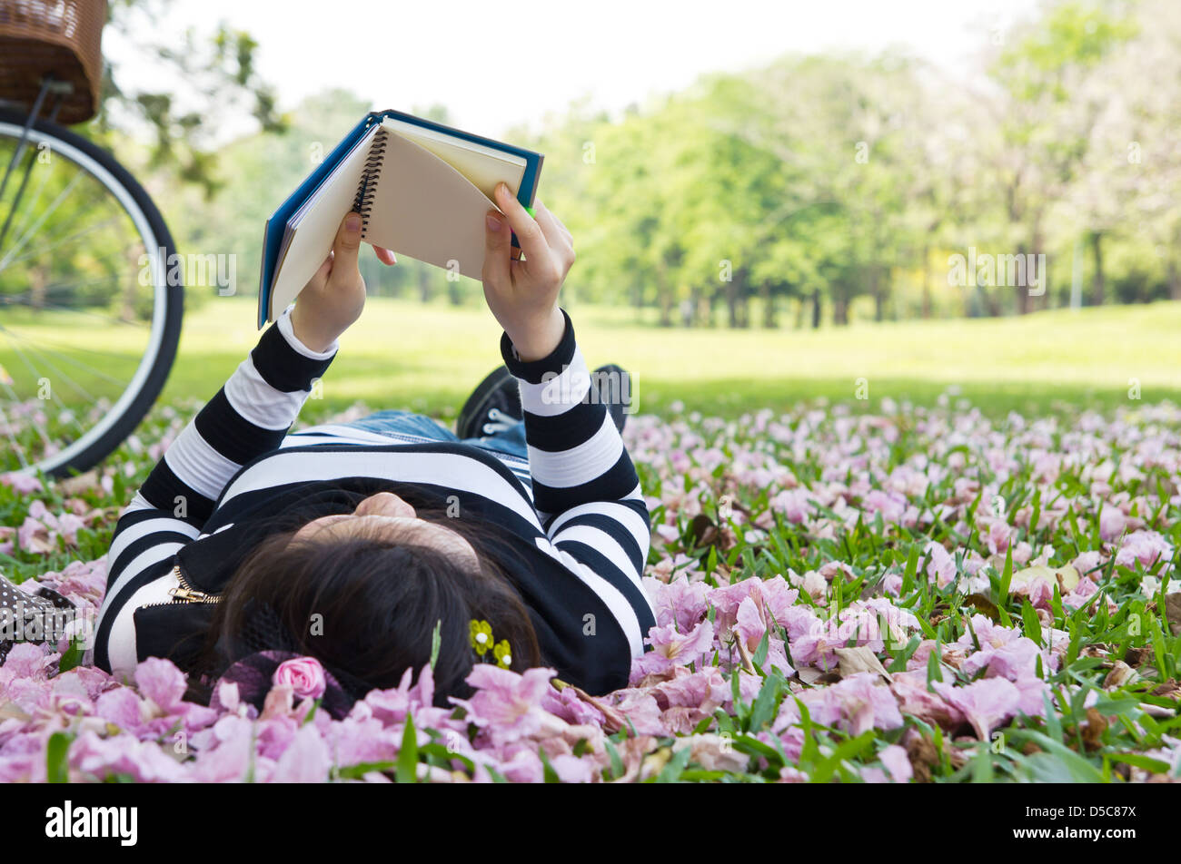 Mujer Asiática leyendo folleto sobre el césped Foto de stock