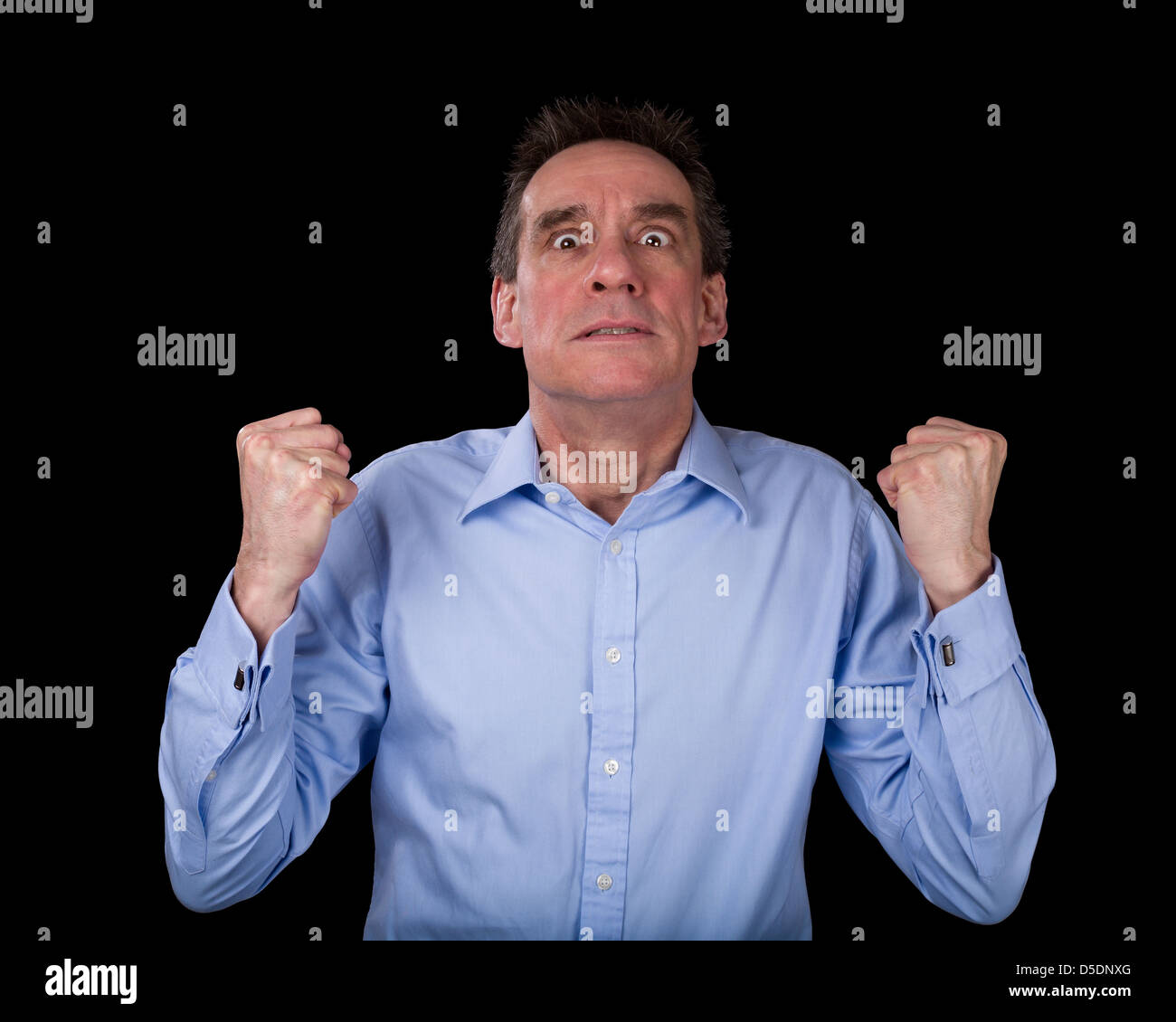Hombre de negocios de mediana edad frustrado agitando puños en ira fondo negro Foto de stock