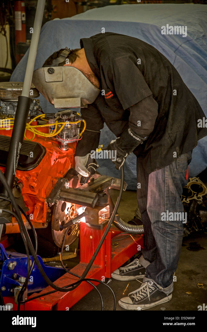 Un jovencito de soldadura de arco un motor de apoyo en una escuela secundaria de clase auto shop en San Clemente, CA, Foto de stock
