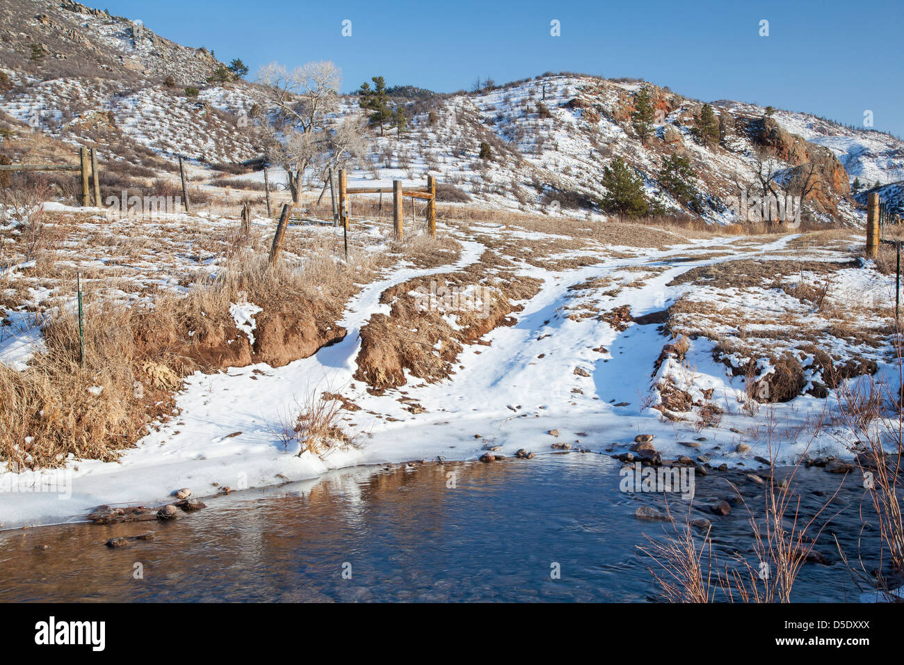 Ranch Road cruzando arroyo en un valle de montaña, paisaje invernal, Nido de Águila Rock Espacio Abierto, Larimer County, Colorado Foto de stock