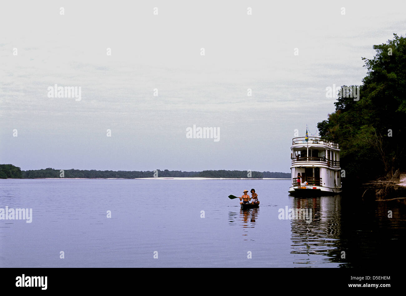 Dos mujeres remar en canoa hacia una touring casa flotante en el Río Negro  Río Amazonas Brasil Fotografía de stock - Alamy