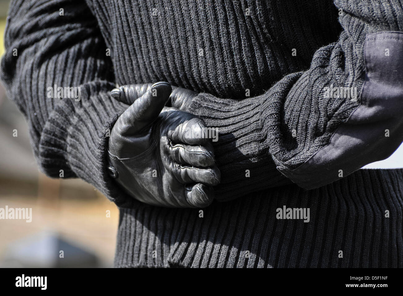 Un hombre vestido con uniforme paramilitar Republicano Irlandés mantiene sus manos enguantadas detrás de su espalda. Foto de stock