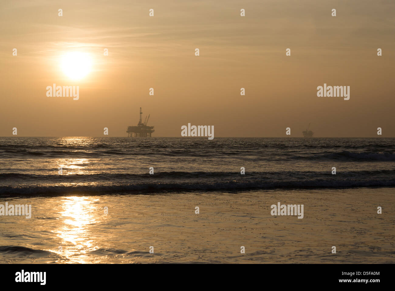 Puesta de sol sobre el Océano Pacífico, con la plataforma de perforación off-shore visible en el horizonte. Foto de stock