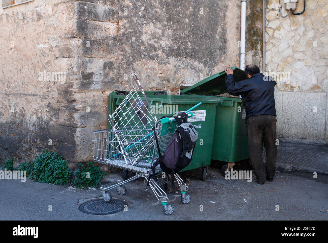 Un desempleado hombre saca un carrito para transportar la basura encontrada en las bandejas. Foto de stock