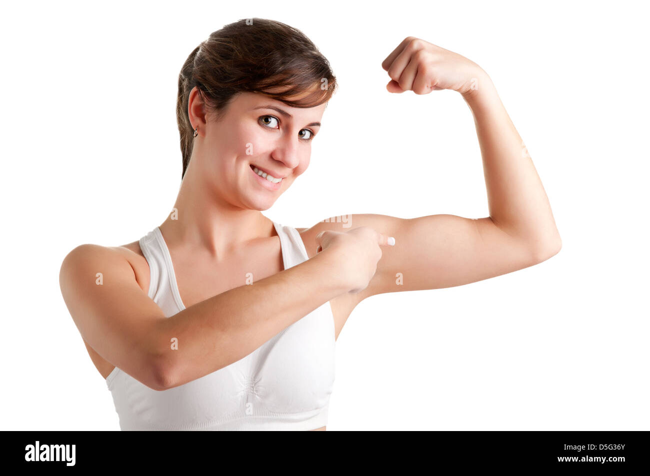 Mujer sonriente y señalando a su bíceps, después de un entrenamiento, aislado en un fondo blanco. Foto de stock