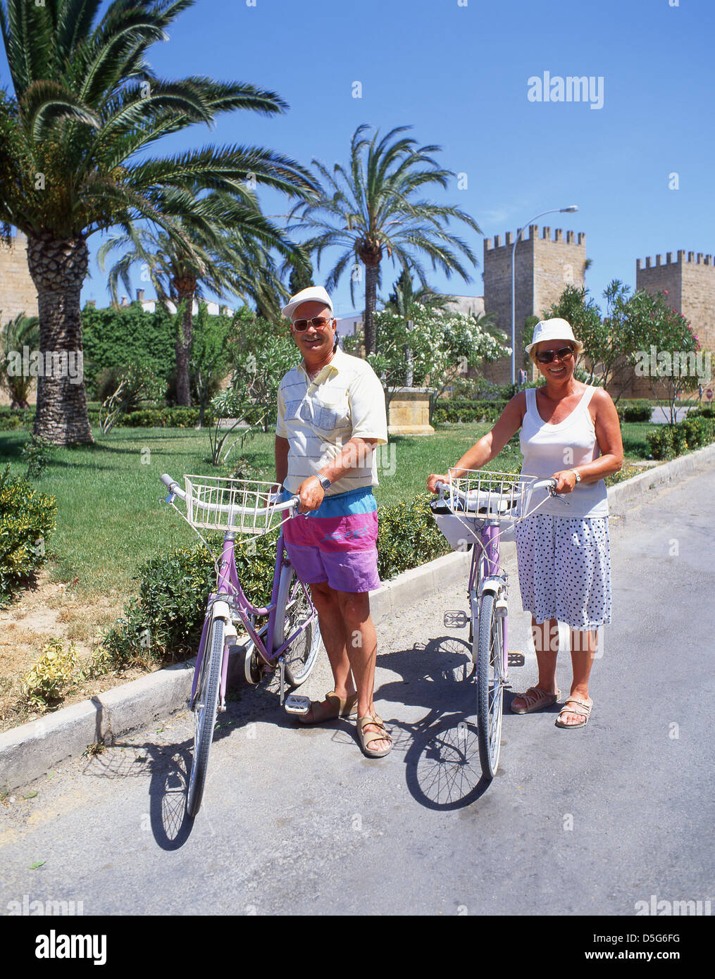 Pareja de ancianos con bicicletas fuera de las murallas de la ciudad vieja, el municipio de Alcudia, Alcudia, Mallorca (Mallorca), Islas Baleares, España Foto de stock