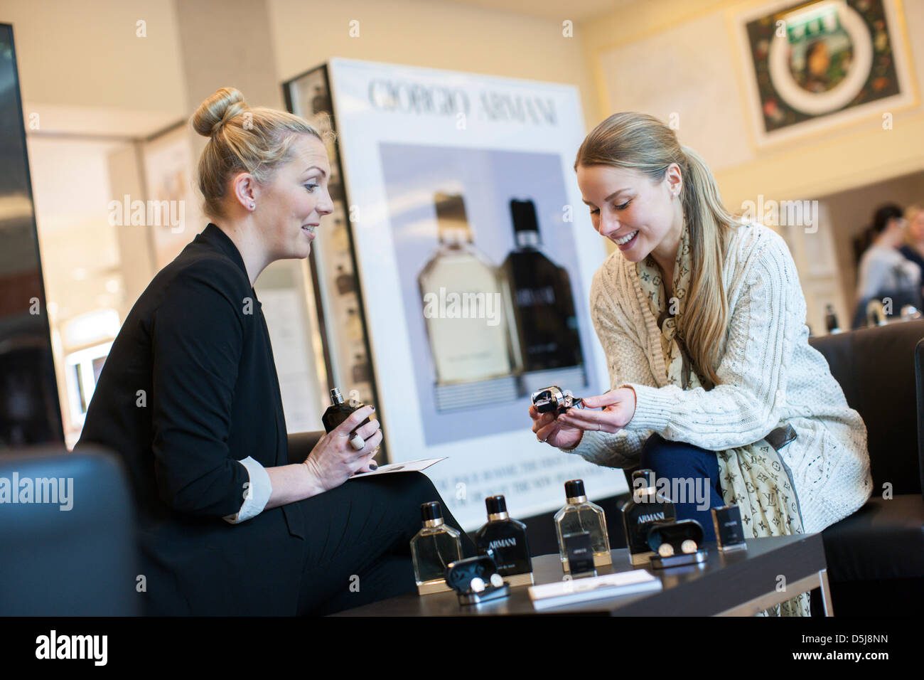 Una joven mujer intenta la nueva fragancia de Giorgio Armani y productos con un consultor. John Lewis, Trafford Centre, Manchester. En el Reino Unido. Foto de stock