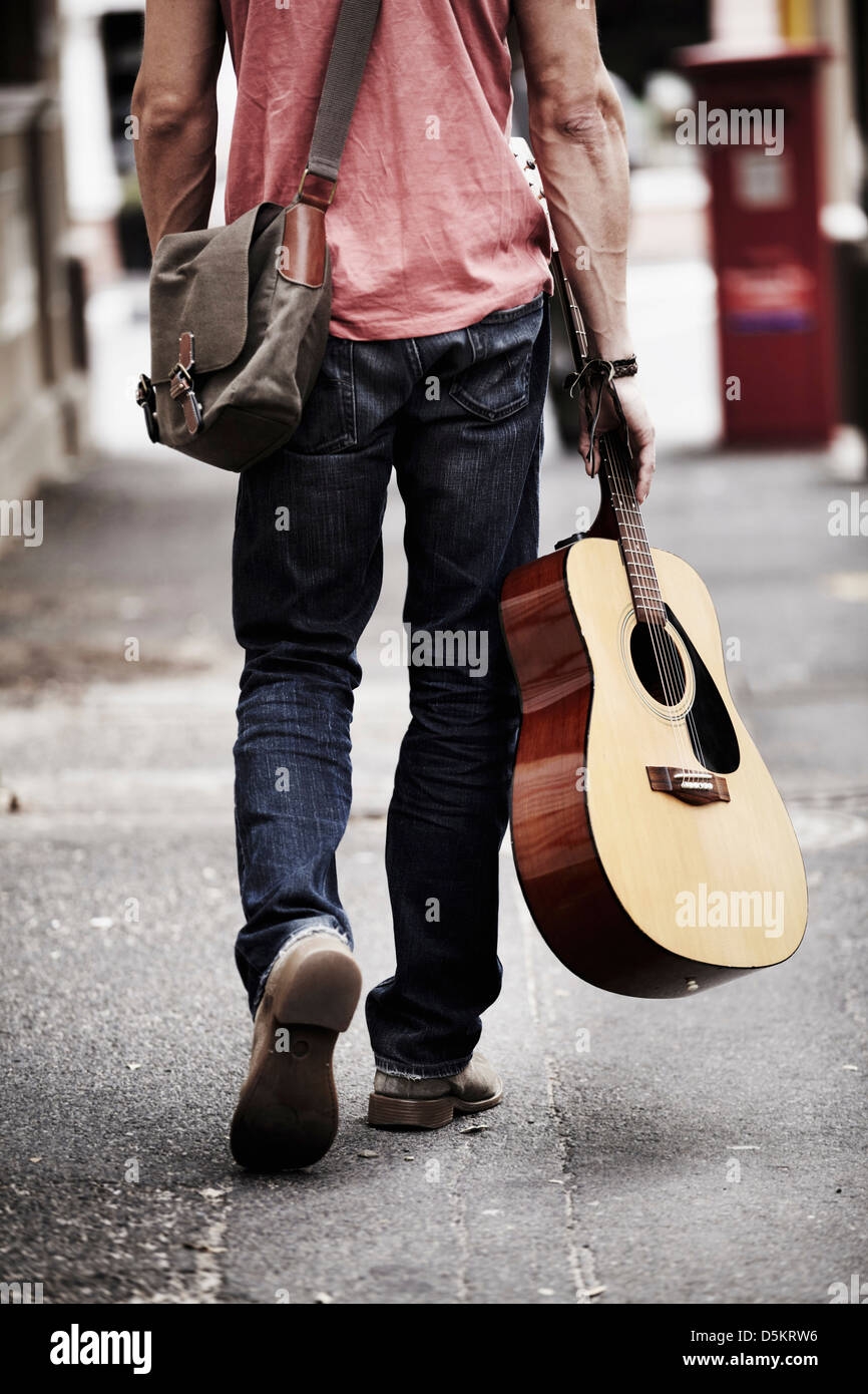 Hombre con Guitarra caminando calle abajo Fotografía de stock - Alamy