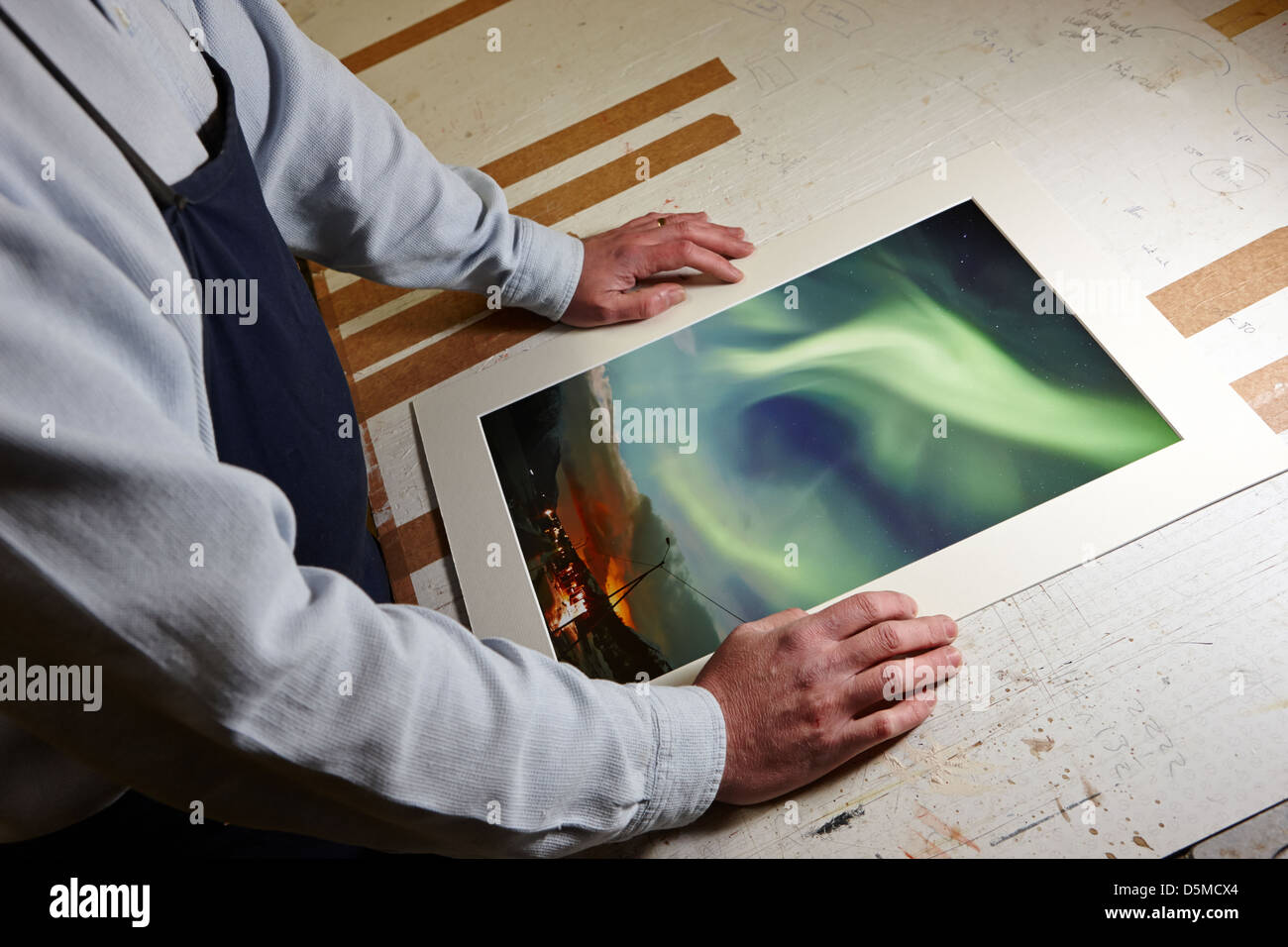 Framer colocando la fotografía de corte a medida en un taller de montaje de encuadre Foto de stock