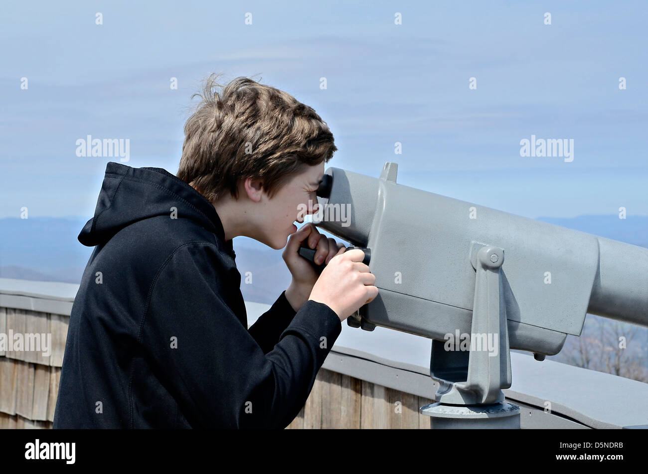 Un muchacho sobre Bald mirando a la vista con un telescopio. Foto de stock