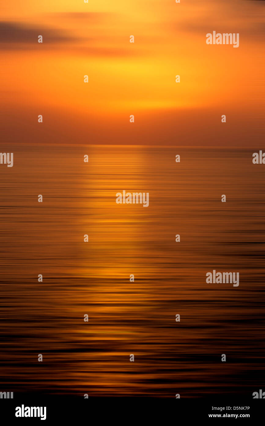 La puesta de sol en la noche, un cielo naranja y rojo en un paisaje al atardecer sobre el océano. Foto de stock