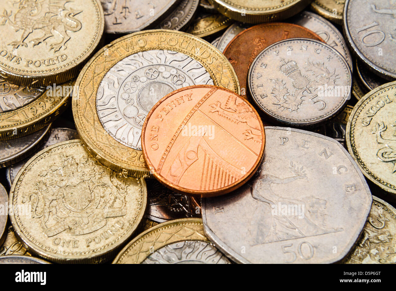 Un solo centavo británico, en el centro, y en la parte superior de una pila de otros actual, moderna (GBP) monedas. Foto de stock
