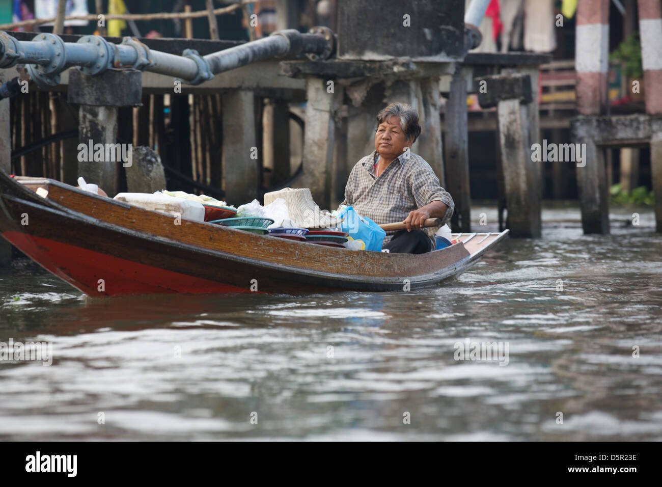 Un viejo hombre tailandés su Sanpan palas en un río en el mercado flotante, cerca de Bangkok, Tailandia. Foto de stock