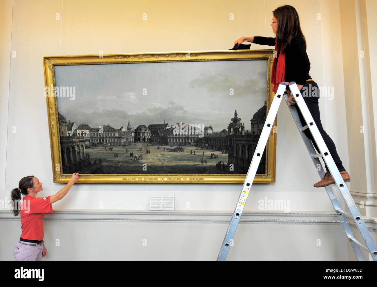Sabine Bendfeldt Restaurators (r) und Kathleen Hohenstein colgar la pintura "El Patio del Palacio Zwinger en Dresden' ('Der Zwingerhof en Dresden') en la imagen de los antiguos maestros Gallsery en Dresden, Alemania, 04 de octubre de 2012. La pintura, que fue creada en 1751/52 por Bernardo Bellotto aka Canaletto, ha sido un año de restauración. Foto: Matthias Hiekel Foto de stock