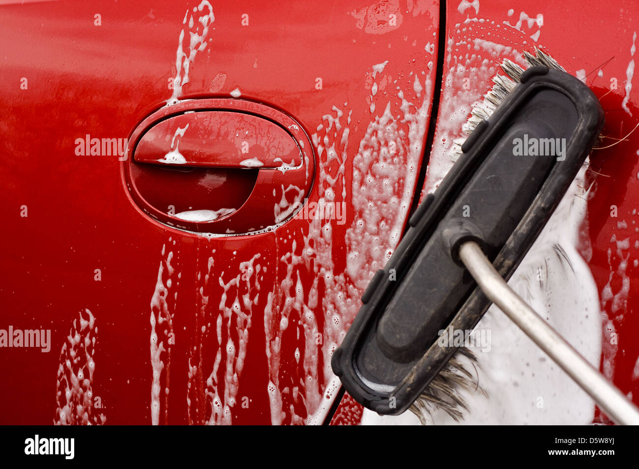 Lavar el coche con un cepillo jabonosa en un lavado de coche de monedas Foto de stock