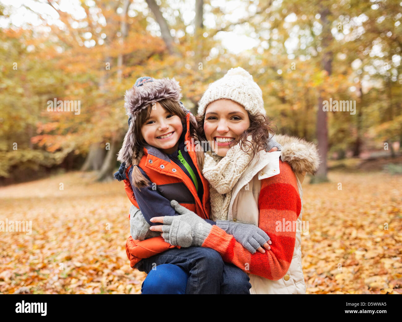 Madre e hija sonriente en hojas de otoño Foto de stock