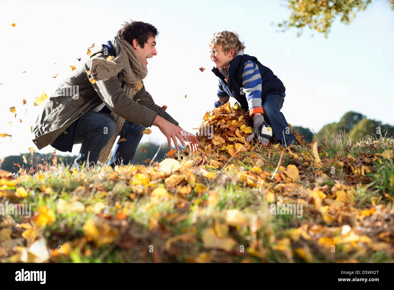 Padre e hijo jugando en hojas de otoño Foto de stock