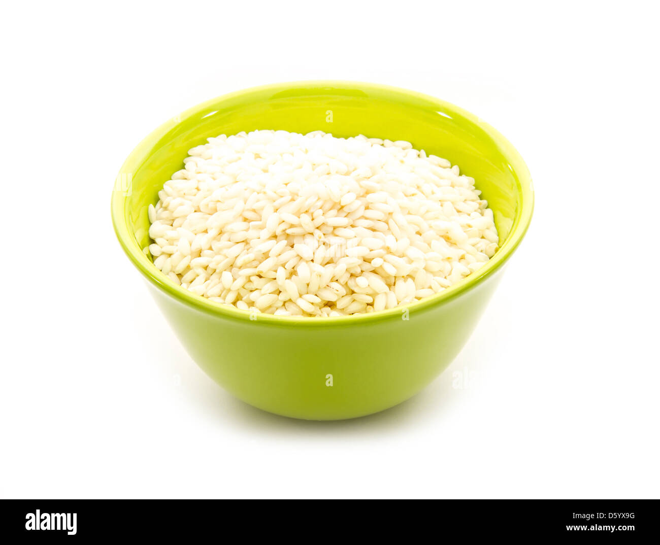 Arroz arborio en verde recipiente aislado sobre fondo blanco Fotografía