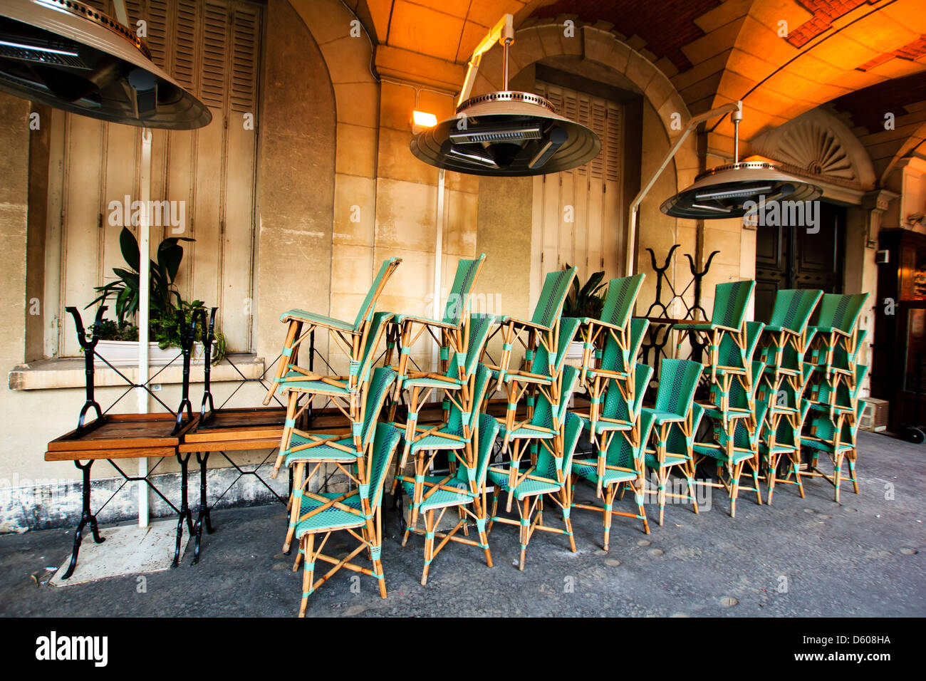 Sillas de mimbre colocados en pilas de café antes de cerrar, el Marais, Place des Vosges, París, Francia Foto de stock