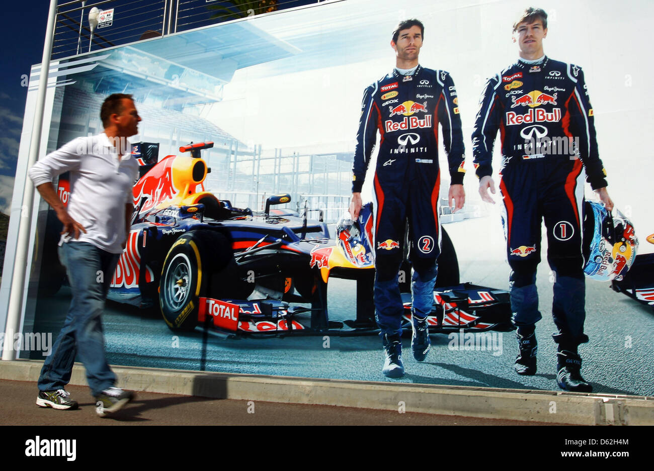 Un hombre camina delante de un cartel sobre el motor de la casa flotante de Red Bull, con las imágenes del piloto de Fórmula 1 alemán Sebastian Vettel (L) y Mark Webber (R) antes del Grand Prix de Fórmula Uno de Mónaco en Montecarlo, Mónaco, 22 de mayo de 2012. El Grand Prix tendrá lugar el 27 de mayo. Fotografía: Jens Buettner dpa Foto de stock