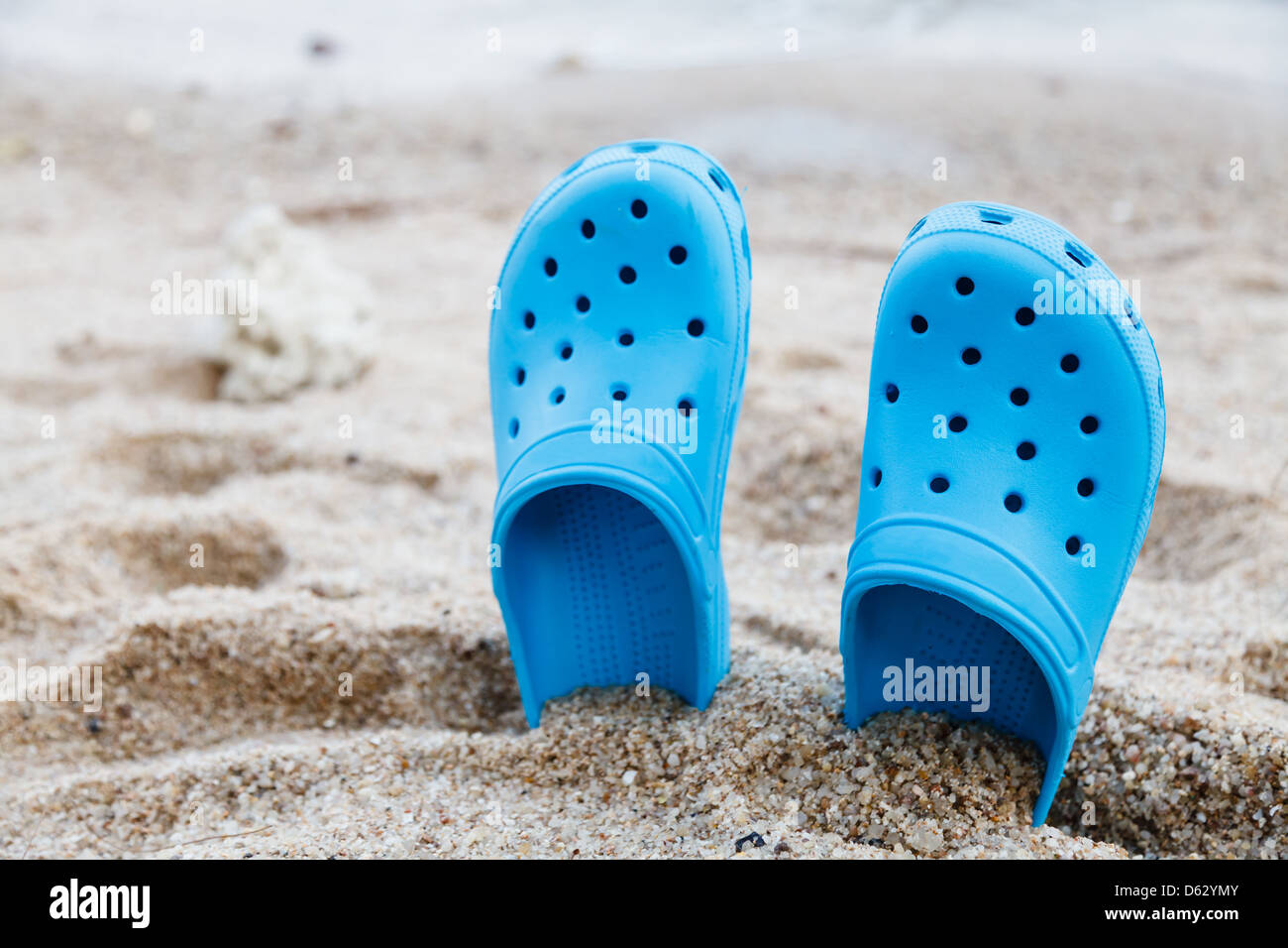 Sandalias azul en la playa con poca profundidad de campo. Foto de stock