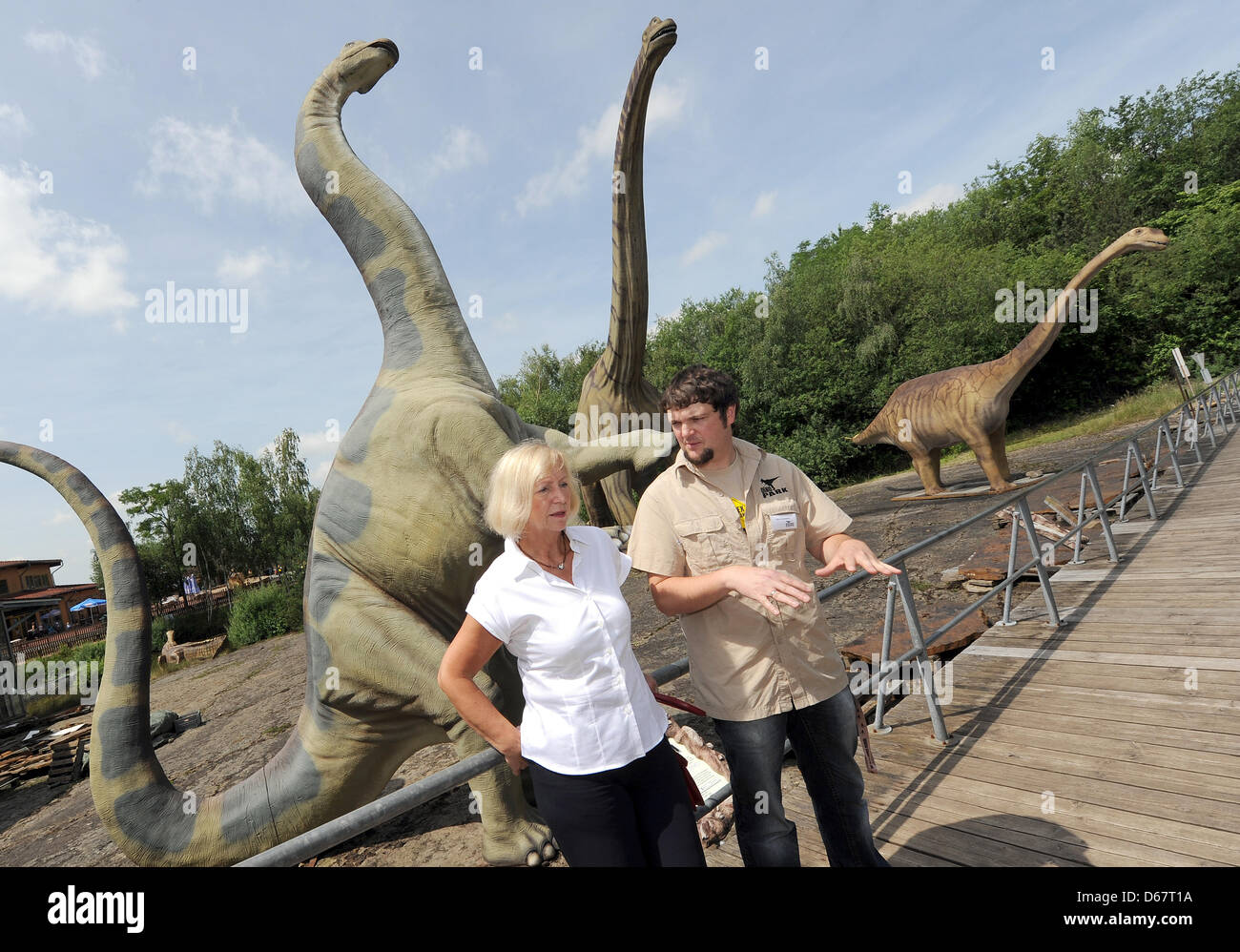 Ministro de Ciencia de Baja Sajonia Johanna Wanka (CDU, L) tiene jefe taxidermista Nils Knoetschke explicar algunos modelos de dinosaurios en el Museo al Aire Libre de dinosaurios en Muenchehagen, Alemania, 28 de junio de 2012. Un esqueleto completo de un Europasaurus es visto en el fondo. Wanka visitó varios sitios de excavación de dinosaurios en la Baja Sajonia. Foto: Holger Hollemann Foto de stock