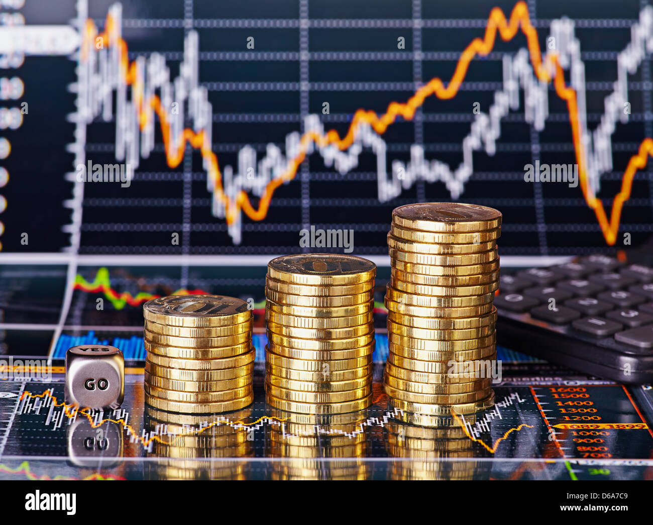 Subida apila monedas, cubos cubo con la palabra GO y calculadora de los gráficos de cotizaciones financieras como fondo. Enfoque selectivo Foto de stock