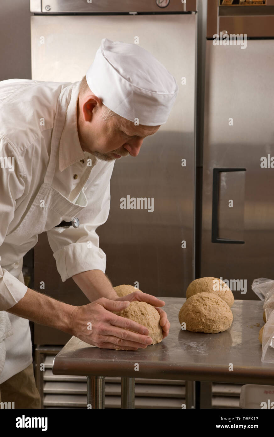 Cocinero profesional Preparando pan fresco en una panadería comercial Foto de stock