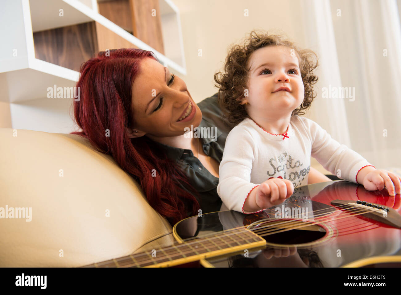 Madre e hija con guitarra en el sofá Foto de stock