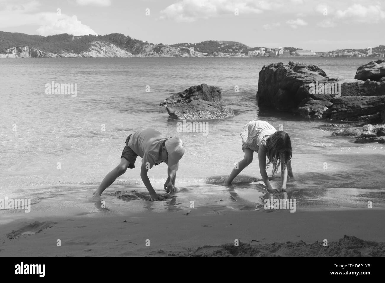 Los niños excavando en la arena de una playa mediterránea Foto de stock