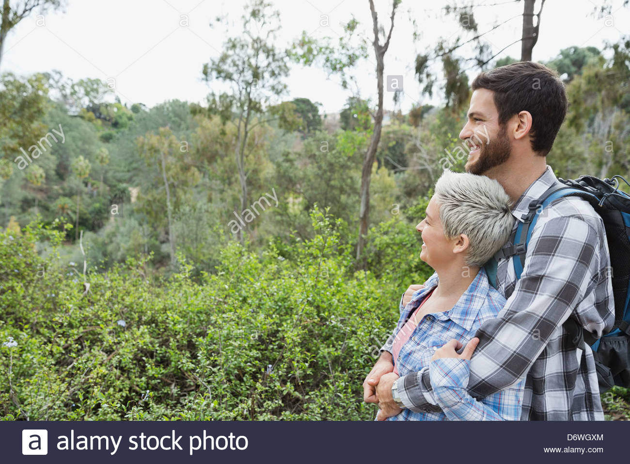 Vista lateral de la pareja mirando a ver en el bosque Foto de stock