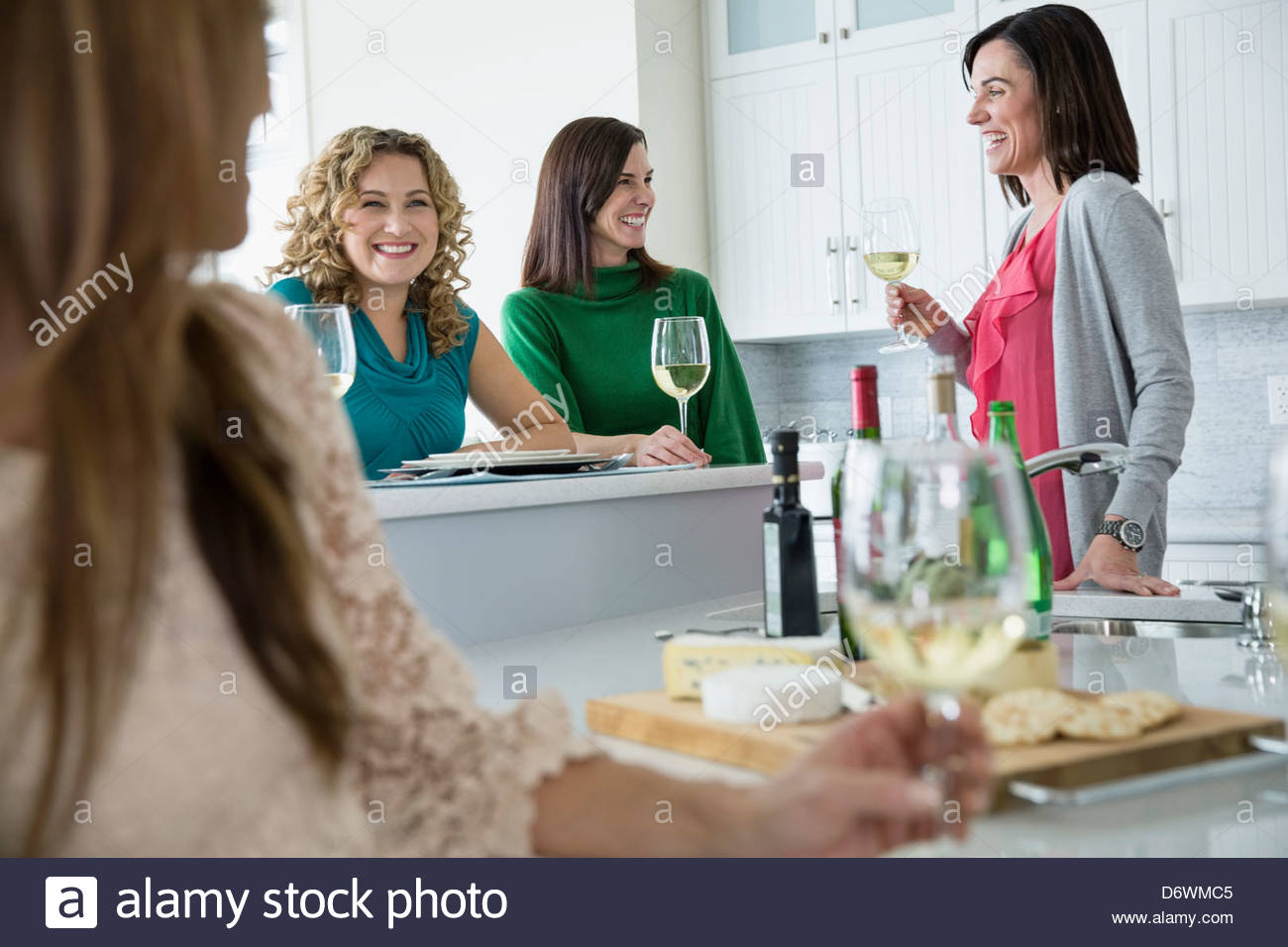 Feliz amigas con wineglasses disfrutando a house party Foto de stock