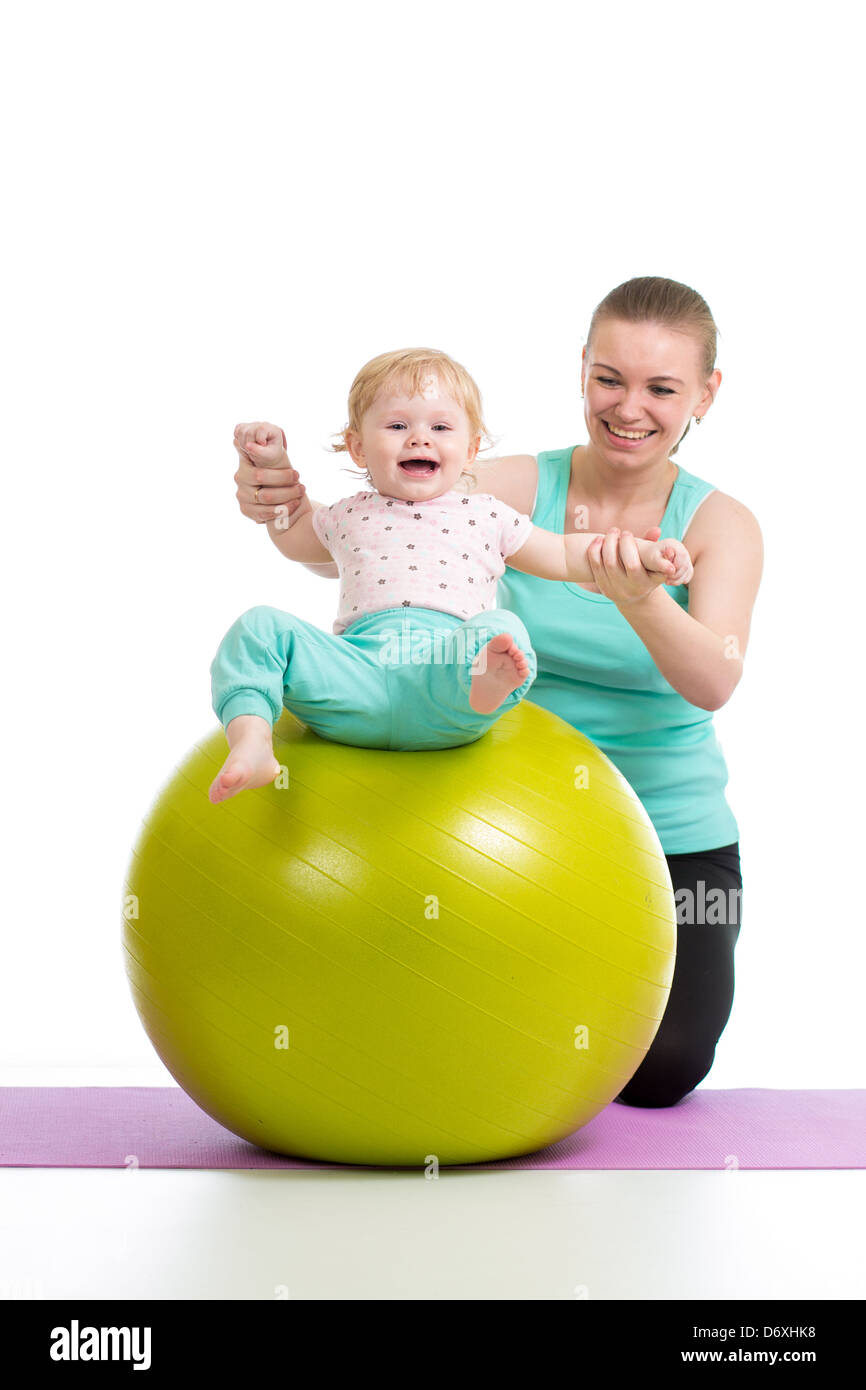 Madre haciendo gimnasia con el bebé sobre la bola de fitness Foto de stock