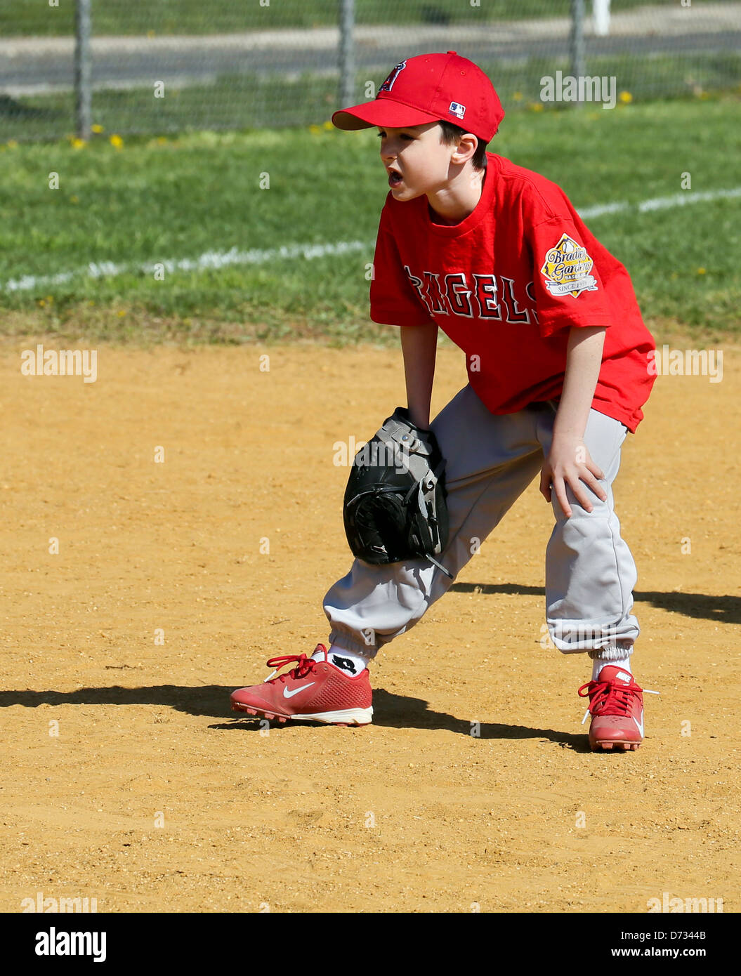 Un tercer baseman Little League Baseball con las manos en las rodillas