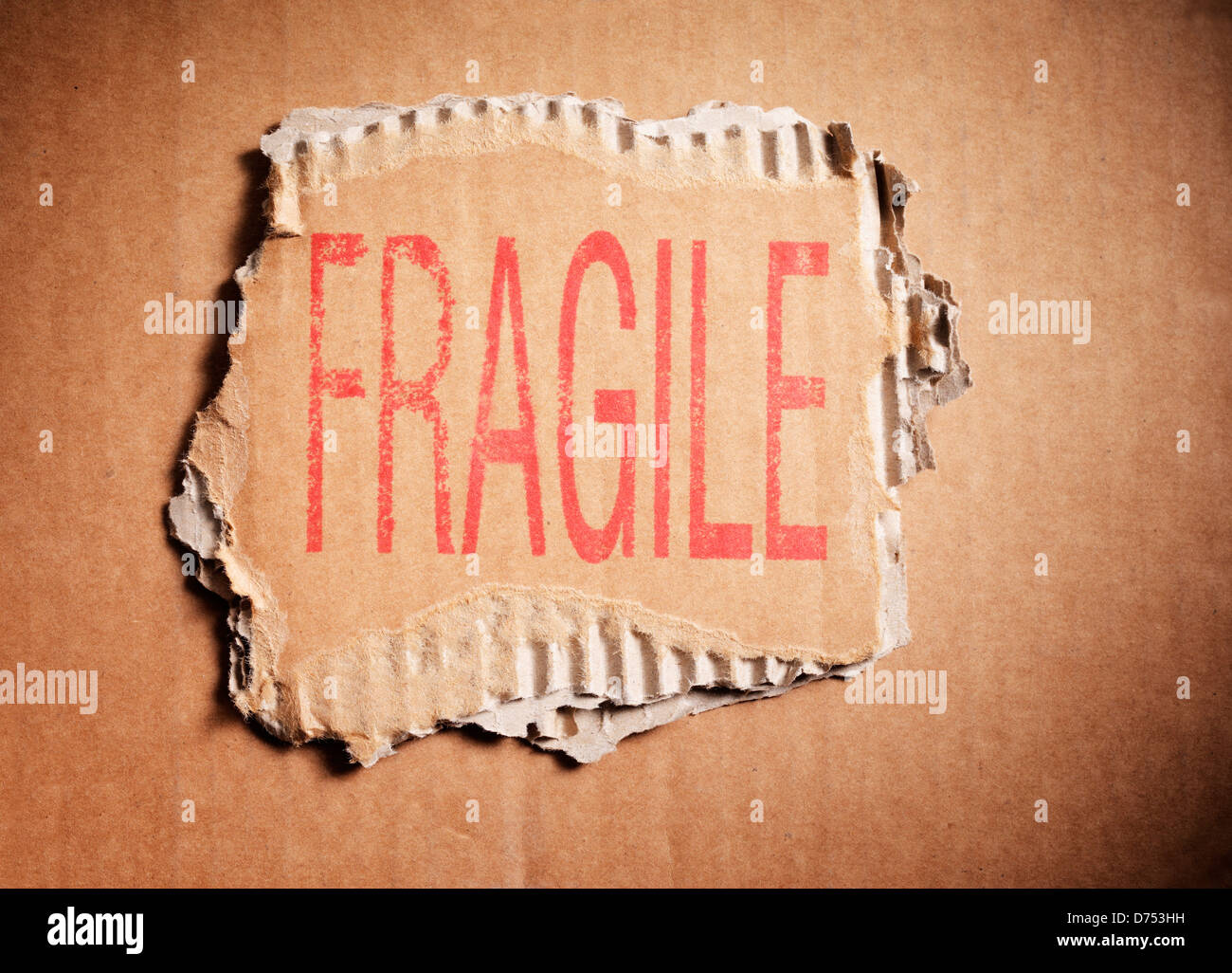 Palabra frágil estampado en un pedazo de cartón ondulado de color marrón. Foto de stock