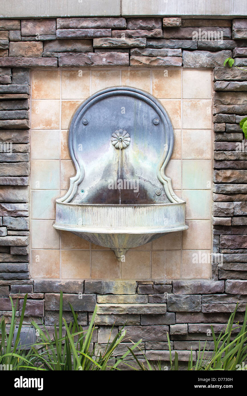 Fuente de agua de pared de estilo toscano en el patio jardín formal Foto de stock