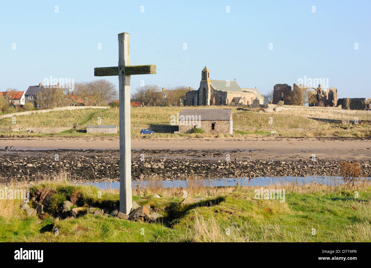 Cruz permanente en St Cuthbert's Isle con Lindisfarne iglesia y convento en el fondo Foto de stock