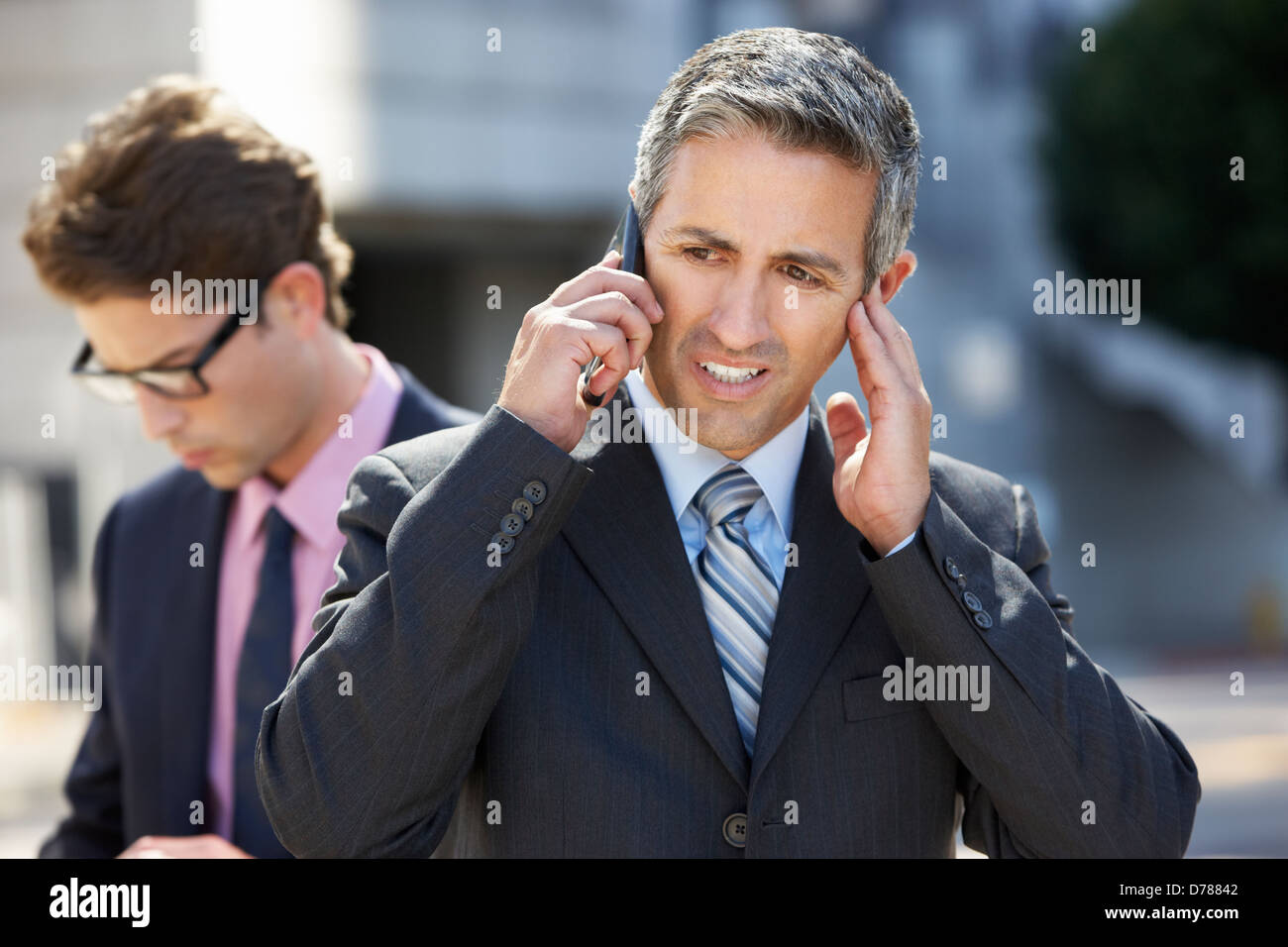 Empresario hablando en teléfono móvil en ambientes ruidosos Foto de stock