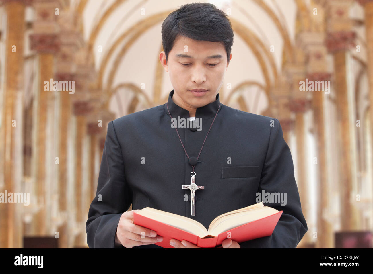 Sacerdote mirando la Biblia en una iglesia Foto de stock