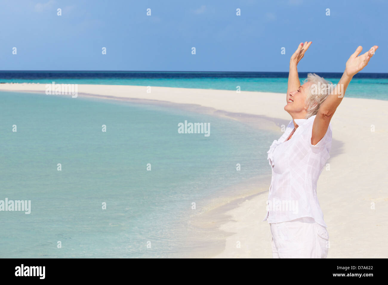 Mujer mayor con los brazos extendidos sobre la hermosa playa Foto de stock