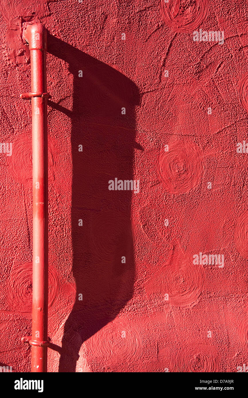 Cadena larga sombra bajo tubo de pared rojo fino arte sol Foto de stock