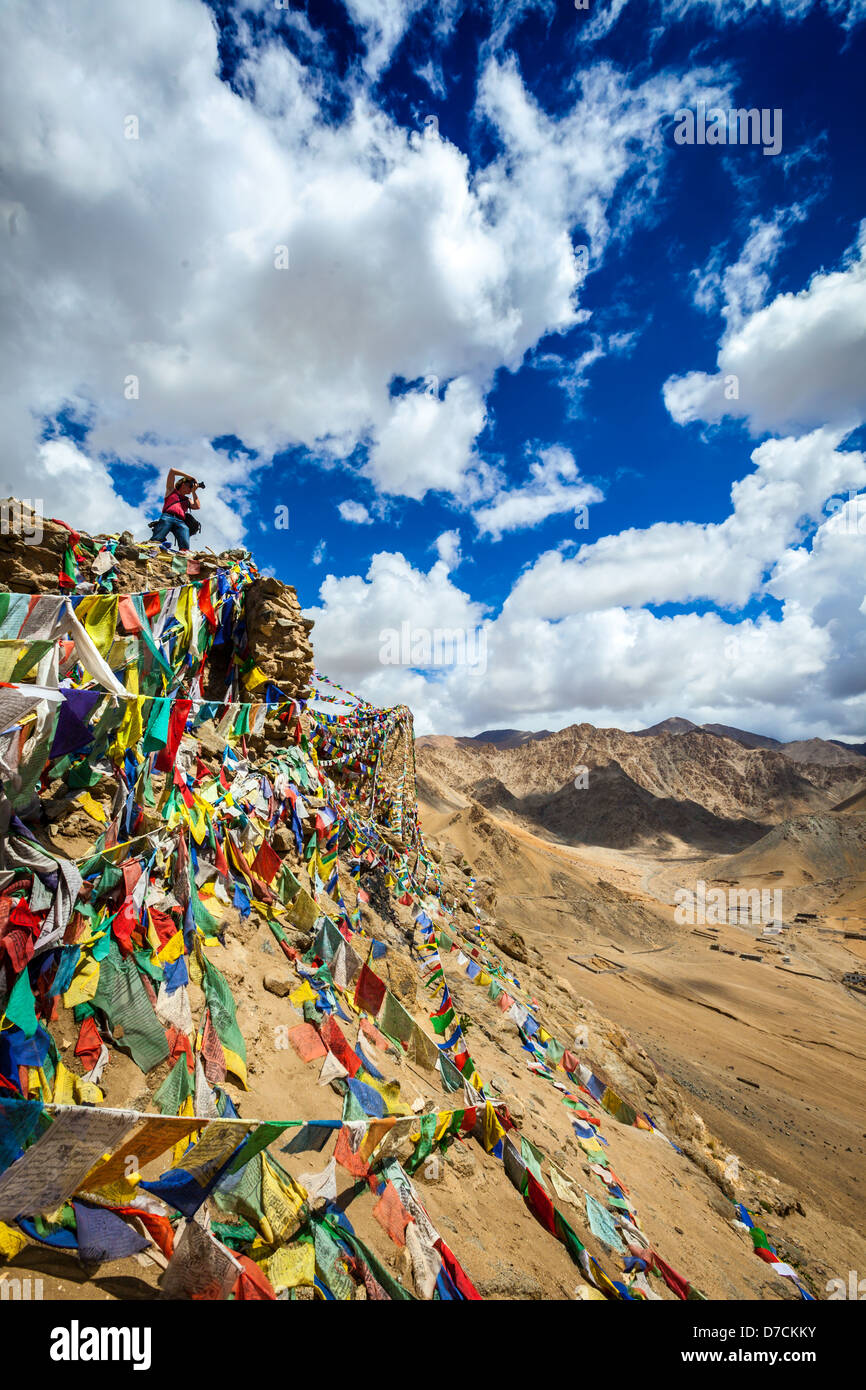 Fotógrafo de viajes tomando fotos en montañas de Himalaya en acantilado con banderas de oración Budista. Leh, Ladakh, Jammu y Cachemira Foto de stock