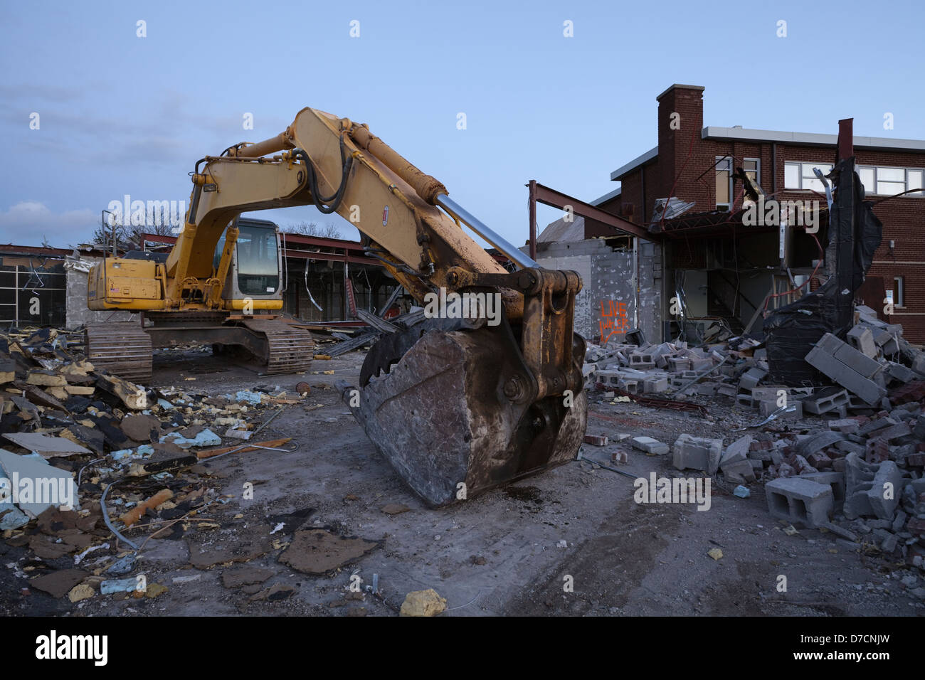 Estacionar la excavadora entre los escombros de un edificio demolidos. Foto de stock